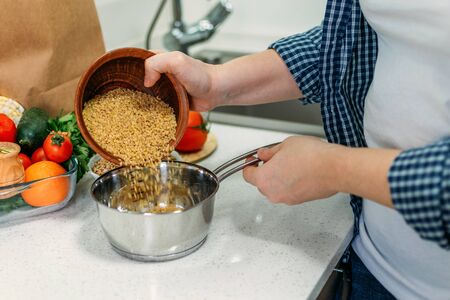 Woman is cooking Ancient Grains Porridge. Heirloom heritage Ancient grains on home kitchen. Health, vegetarian food, dietingの写真素材