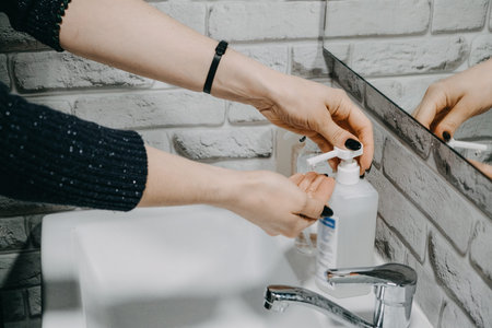 Gel hand sanitisers protect against the new coronavirus. Woman using bottle of antibacterial...
