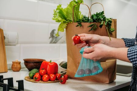 Grocery Delivery Services, online shopping. Home smart food grocery delivery. Woman customer receiving order from courier and unpacks products in the kitchen at home.の写真素材