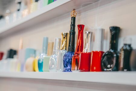 Various Bottles of nail polish on white shelf on shop. Group of bright nail polishes. Set of different nail varnishes on shelves in cosmetic store.の写真素材