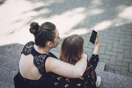 Pride Month, LGBT Lesbian couple love moments concept. Two Young lesbians girls hugging and take selfie on smartphone outdoors.の写真素材