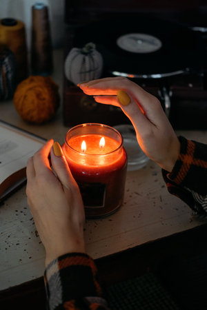 Winter cozy mood concept. Still life details in home interior of living room. Scented Soy Aromatherapy Candle and cup of tea with steam on table. Cozy autumn or winter conceptの写真素材