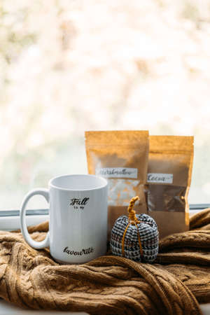 Work-life balance, cosy at home, relaxing indoors concept. Winter fall cozy mood concept. Still life details with Scented Aromatherapy Candle, cacao and cup and knitted sweaterの写真素材