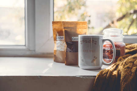 Work-life balance, cosy at home, relaxing indoors concept. Winter fall cozy mood concept. Still life details with Scented Aromatherapy Candle, cacao and cup and knitted sweaterの写真素材