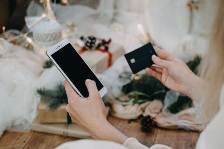 Online shopping, Black Friday sale, Christmas deals concept. Close up of female hands holding cell telephone with blank copy space screen and credit cardの写真素材