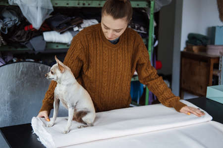 A fashion designer with a pet dog in the studio.の写真素材
