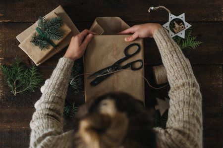 Christmas wrapping idea, xmas wrapping workspace. Female hands wrap gift box in kraft recycled...