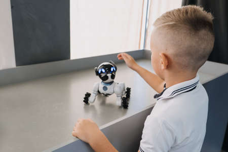 Little boy playing with interactive Remote Control Robot Dog Toy. Kid and smart Dancing Robot Toy, Imitates Animals mini Pet Dog Robot. Kropivnitskiy, Ukraine, July 28, 2020のeditorial素材