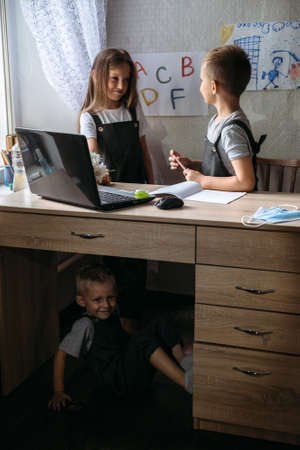 Distance learning, home education, remote lessons concept. Two schoolchildren near open laptop and watch a video lesson, listen to teacherの写真素材