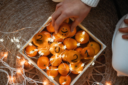 2021 goals, new year resolution, start planning new year, 2021 is Coming. Box of oranges, tangerines with numbers 2021, garland lights and hands with smile on orange.の写真素材