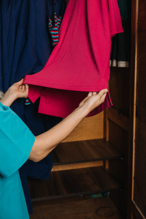 Slow, eco sustainable fashion, Organizing Your Closet, minimal wardrobe. Woman choosing clothes from closet at homeの写真素材