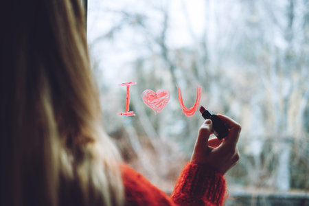 Love at distance, loneliness in self-isolation in the time virus. Woman draws heart and I love you...