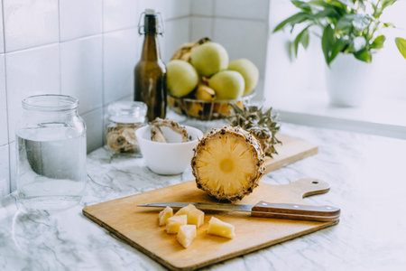 Fermented pineapple kombucha drink tepache. Cooking process of homemade probiotic superfood pineapple beverage. Drink jar and sliced pineapple on home kitchenの写真素材