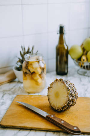 Fermented pineapple kombucha drink tepache. Cooking process of homemade probiotic superfood pineapple beverage. Drink jar and sliced pineapple on home kitchenの写真素材