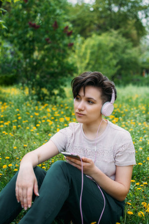 Young woman in headphones and with smartphone using audio chat social networking app, listening...