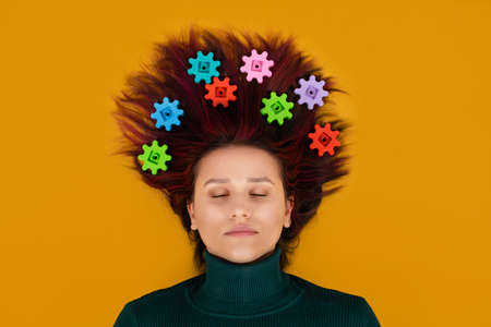 Neurophysiology, neuroscience, Brain, psychology, mental health, creativity, idea concept. Woman with gears in hair on orange backgroundの写真素材