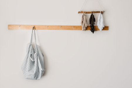 Minimalistic neutral tones mockup with organic cotton eco tote shopper bag on wooden hanger on a...