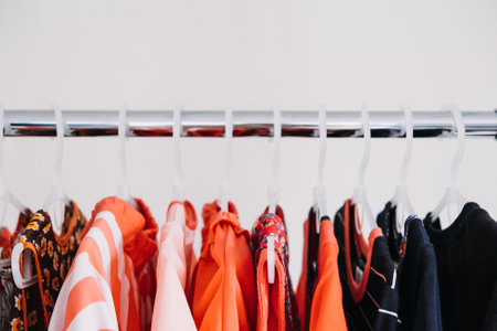 Circular Economy, Second hand, Fast fashion, Sustainable fashion. Many second hand red colors clothes hanged on clothes rackの写真素材