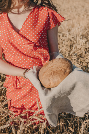 Homemade sourdough Bread Recipe. Homemade Artisan Bread in woman hands on wheat field background....