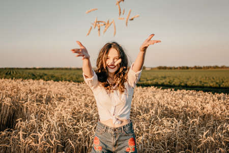 Wheat crop, harvest, Harvesting agriculture, economy. Young brunette woman with hands full of ripe wheat seeds in cereal field ready harvestの写真素材