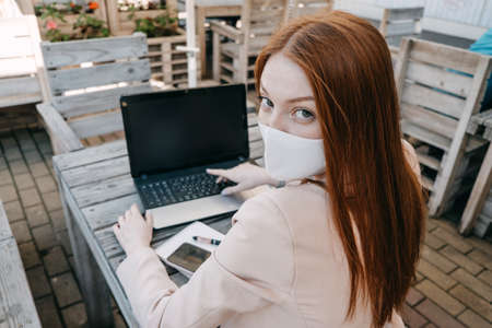 Outdoor work areas, workplace. Take office Outside, Work Moves Outdoors During Pandemic. Mobility, autonomy, work remotely. Redhead business woman working at laptop outdoorsの写真素材
