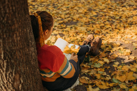 Young plus size woman reading book in fall autumn park in sun lights.