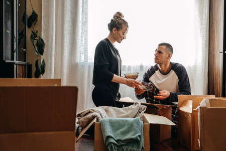 Moving day, new home, unpacking boxes. Happy couple in their new apartment is having fun with cardboard boxes. Cheerful young couple in new house at moving dayの写真素材