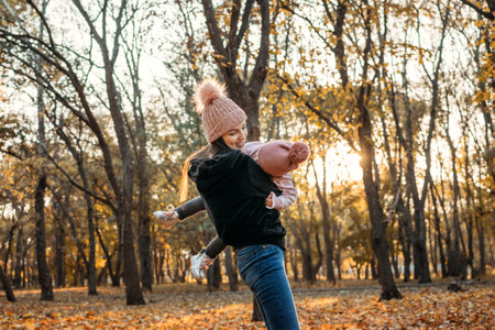 Family Fall Social Distancing Activities. Happy family mom and toddler baby girl playing outdoors in fall park. Little girl and her mother in the autumn park. Fall activities for toddlers.の写真素材