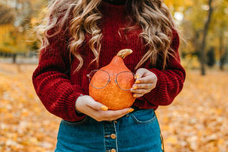 Faceless portrait of woman holding orange halloween pumpkin on autumn park yellow trees background. Fall autumn Thanksgiving Halloween conceptの写真素材