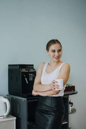 Employee care, caring in the workplace, Engagement and Retention. Young business woman drinking coffee in office break room during lunchtimeの写真素材