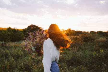 Healing Power of Nature, Benefits Of Ecotherapy, Nature Impact Wellbeing. Happy young girl holding wildflowers bouquet, relaxing and enjoying lifeの写真素材