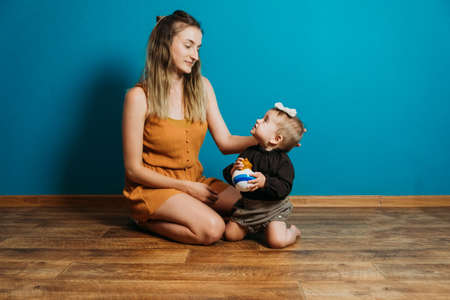 Baby fashion, choose dress and accessories. Mom dresses the little toddler baby girl at home. Mother and little fashion baby girlの写真素材