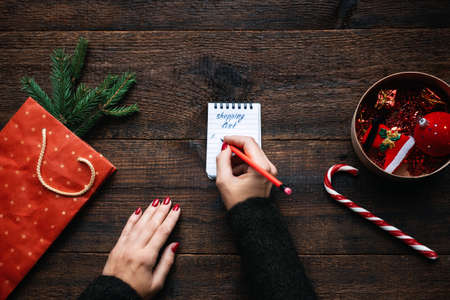 Christmas shopping list. Christmas Shopping on Budget. Christmas Money Saving Tips. Female hands with small notepad and text shopping listの写真素材