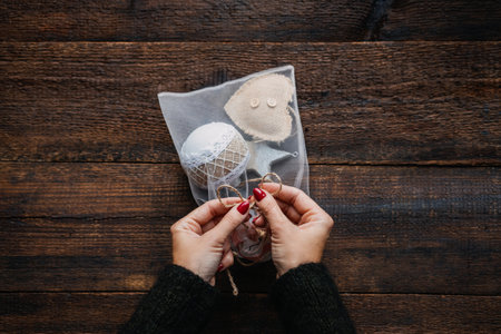 Eco-friendly Christmas gift wrapping. DIY Gift Wrap Eco-Friendly ideas. Female hands with Christmas gift balls and wooden toys in mesh reusable produce net bagsの写真素材