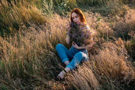 Celebration of Self, inner beauty, self-love, self-soothing, self-celebration. Happy young girl holding wildflowers bouquet, relaxing and enjoying lifeの写真素材