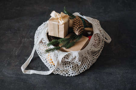 Zero waste, Sustainable, green, eco-friendly Christmas. Eco friendly mesh net shopping bag with craft gift boxes and green fir tree branch. Mesh Reusable Cotton Grocery Bag with Christmas giftsの写真素材
