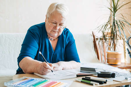 Hobby Ideas for Older People. Retirement Hobbies, Pastimes for Seniors. Activities for Seniors with Limited Mobility. Mature, elderly woman practices spelling words, online hand lettering classの写真素材