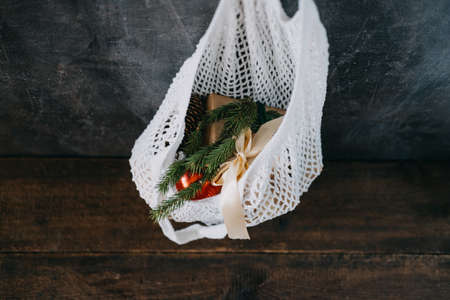 Zero waste, Sustainable, green, eco-friendly Christmas. Eco friendly mesh net shopping bag with craft gift boxes and green fir tree branch. Mesh Reusable Cotton Grocery Bag with Christmas giftsの写真素材