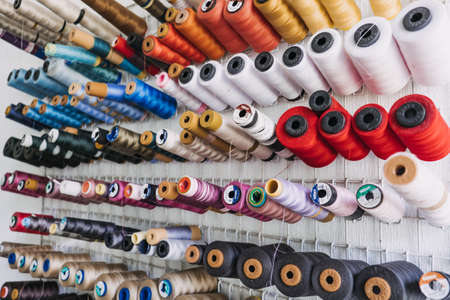 Many thread spool, cotton yarn roll, sewing material on wall in dressmaking studio, fabric. Colorful embroidery thread spool in sewing studio. Kropivnitskiy, Ukraine, October 29, 2021のeditorial素材