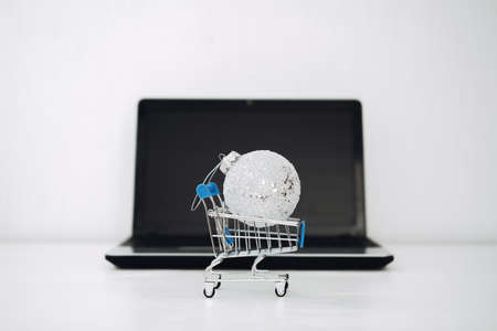 Christmas online shopping, winter sale, black Friday. Christmas ornament toy ball in shopping cart on black Laptop blank screen background.の写真素材