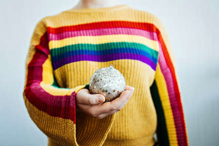 LGBT Pride Christmas. Faceless portrait of Person in Rainbow LGBT flag sweater with Christmas ornament ball in hands.の写真素材