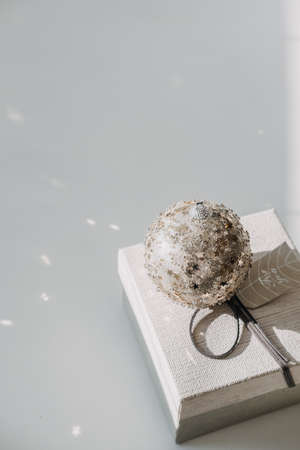 Christmas minimal web banner with Christmas ornament ball and gift box on light background. Christmas gift box and sparkles Xmas ornament ball on white background. Holiday bannerの写真素材