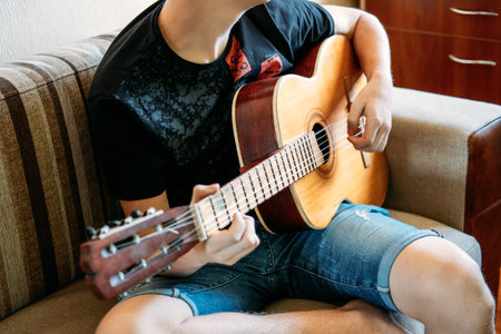 Guitar lessons for beginners. Close up of hands playing guitar. Online Guitar Lessons, enjoying...