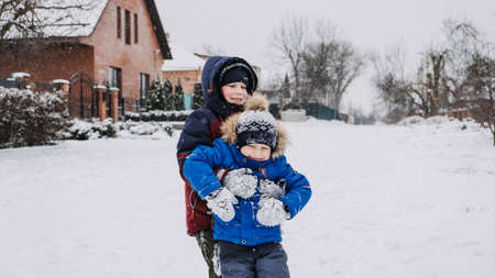 Outdoor winter activities for kids. Kids playing in the suburbs, winter backyard gathering. Boys having fun with snow. Selective focusの写真素材