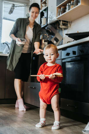 Happy mother and little baby toddler girl making christmas cookies in home kitchen. Mother and little girl baking Christmas gingerbread pastry for family dinner on Xmas eve.の写真素材