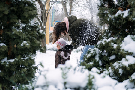 Winter walks with babies and young children. Baby toddler in Winter, How to Protect kids in Cold Weather. Mother and baby girl daughter walking in the winter parkの写真素材