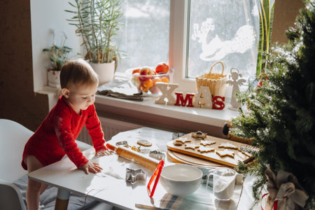 Cute little baby toddler girl making christmas cookies in home kitchen and play with dough. Mother and little girl baking Christmas gingerbread pastry for family dinner on Xmas eve.の写真素材