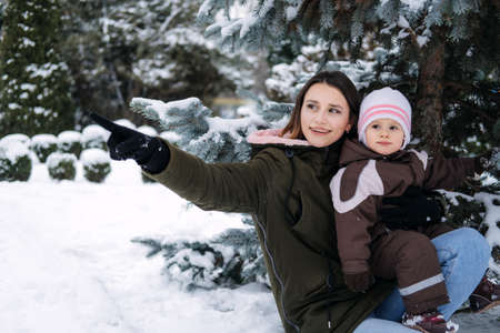 Best Outdoor Winter Activities with Baby. Baby toddler in Winter, How to Protect kids in Cold Weather. Mother and baby girl daughter walking in the winter parkの写真素材