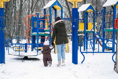 Best Outdoor Winter Activities with Baby. Baby toddler in Winter, How to Protect kids in Cold Weather. Mother and baby girl daughter walking in the winter parkの写真素材