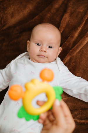 First Rattle Toy for Baby. Rattles and Teethers, Teething Toys. Cute newborn baby girl looking at...